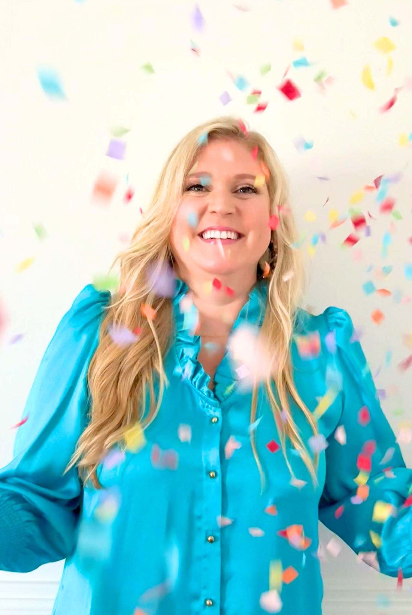 Woman wearing blue Harper Long Sleeve Dress with ruffle neckline and gold buttons surrounded by colorful confetti