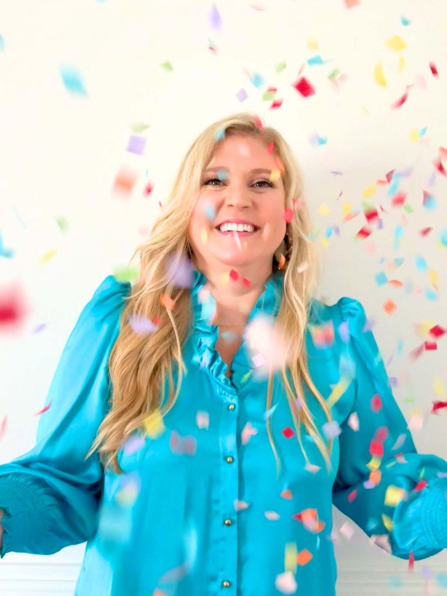 Woman wearing blue Harper Long Sleeve Dress with ruffle neckline and gold buttons surrounded by colorful confetti