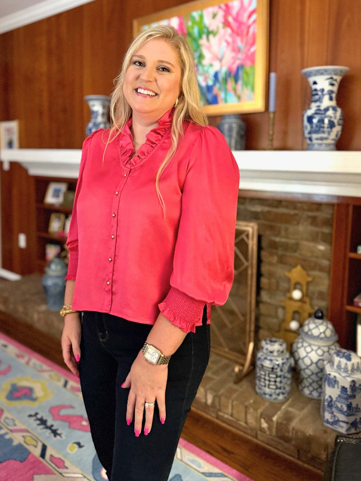 Woman wearing pink Harper Top long sleeve with ruffle neckline and gold buttons indoors