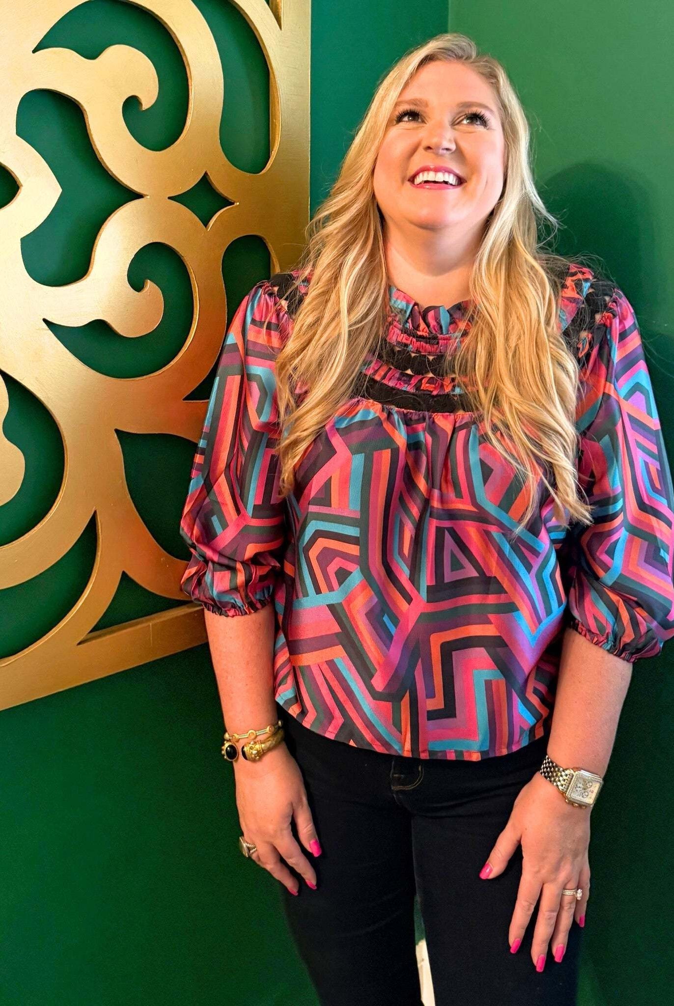Woman wearing colorful geometric patterned Sarah Top with three-quarter sleeves against green background