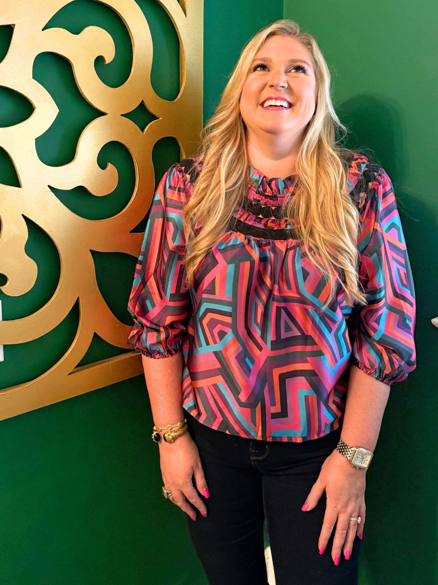 Woman wearing colorful geometric patterned Sarah Top with three-quarter sleeves against green background